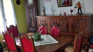 Ein Essbereich mit einem Holztisch, roten Sitzmöbeln, einer Zierkommode und einem an der Wand befestigten Spiegel.