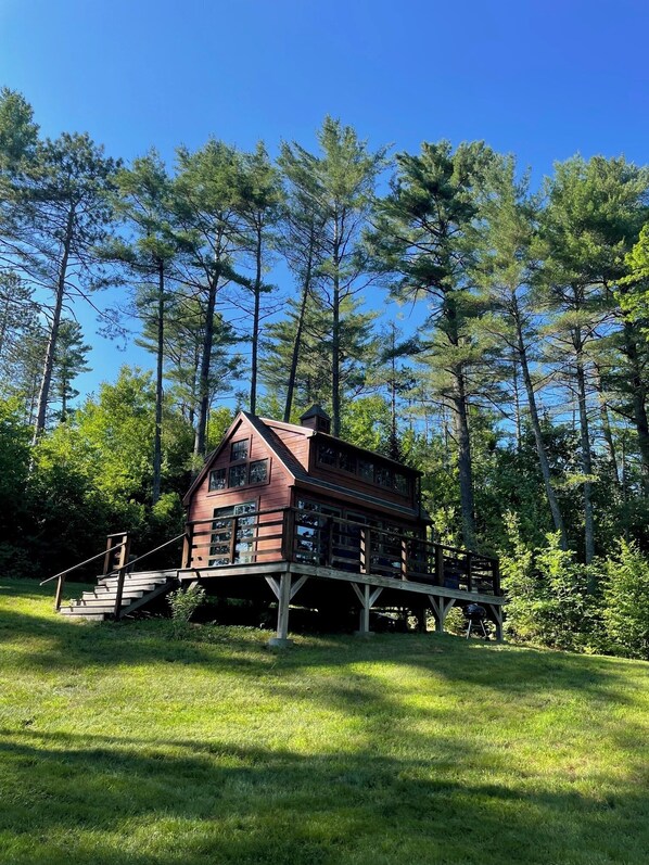 A cabin with a wooden deck and stairs leading up to it, surrounded by tall trees. - Rustic and Sustainable mini Cabin (i.e. no electricity) (Belgrade)