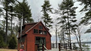 A rustic cabin with a wooden deck and a staircase leading to the entrance.