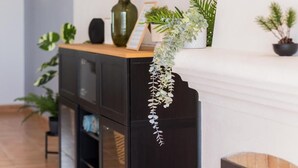 A modern interior with a wooden cabinet, a white fireplace mantel with a hanging plant, and a framed picture on the wall. - Casa Londamba | Meia Praia Beach House | Lagos Sea View (Lagos)