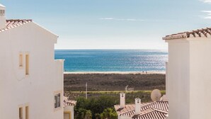 A coastal view from a building with white walls and terracotta roofs, overlooking a beach and the sea. - Casa Londamba | Meia Praia Beach House | Lagos Sea View (Lagos)