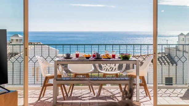 A balcony with a table set for breakfast overlooking the sea. - Casa Londamba | Meia Praia Beach House | Lagos Sea View (Lagos)