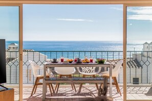 A balcony with a table set for breakfast overlooking the sea. - Casa Londamba | Meia Praia Beach House | Lagos Sea View (Lagos)