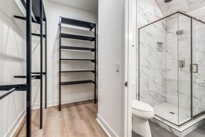 Une salle de bain dotée d’une douche à parois de verre, de toilettes et d’une étagère avec plusieurs niveaux.