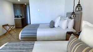 Habitación de hotel con dos camas, kitchenette y lámparas colgantes.