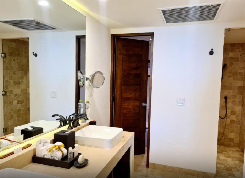 Un baño moderno con un espejo grande, dos lavamanos y una zona de ducha.
