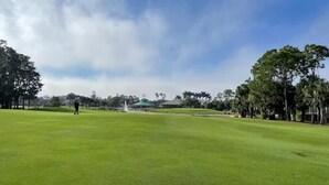 A golf course with a putting green, trees, and a distant building. - House for long-term rentals in Naples, Florida (Naples)