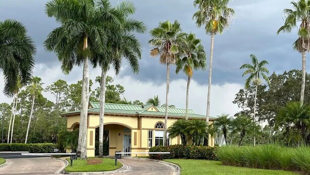 A yellow building with a green roof, surrounded by palm trees and a well-maintained lawn. - House for long-term rentals in Naples, Florida (Naples)