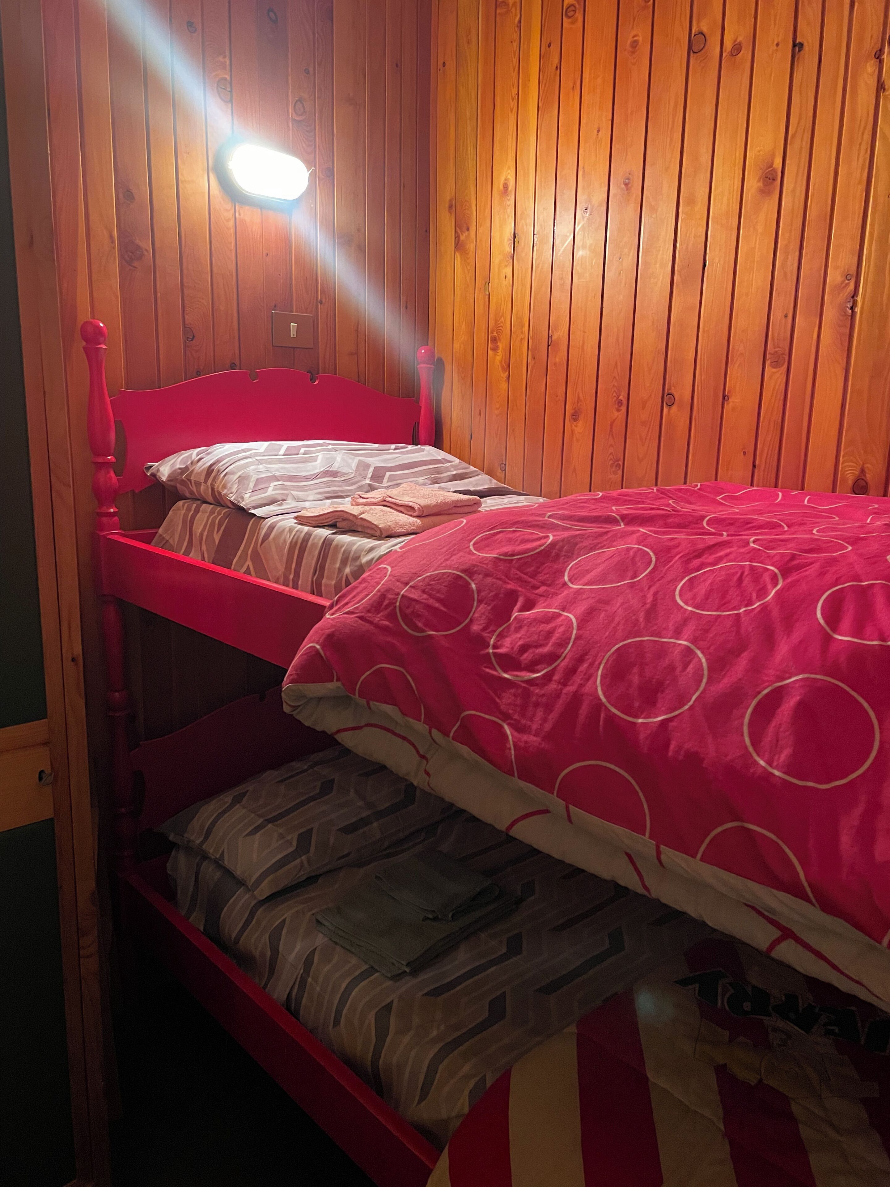 Uma cama beliche com cabeceira vermelha e um beliche inferior com cobertor estampado.