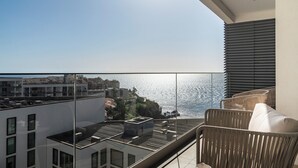 A balcony with a view of the sea and buildings, wicker chairs, and a table with cups. - With shared swimming pool and gym - Acqua Residence IV (Funchal)