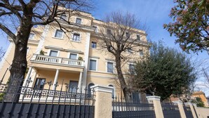 Un immeuble à plusieurs étages doté de balcons, d’une entrée sécurisée et d’arbres au premier plan.