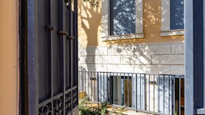 Un bâtiment à la façade jaune, doté d’un portail en métal noir et d’un petit jardin planté.