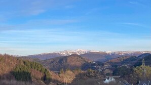 A mountainous landscape with snow-capped peaks, a valley with sparse vegetation, and a small settlement with houses and power lines. - Lovely home in Flaktveit with WiFi (Flaktveit)