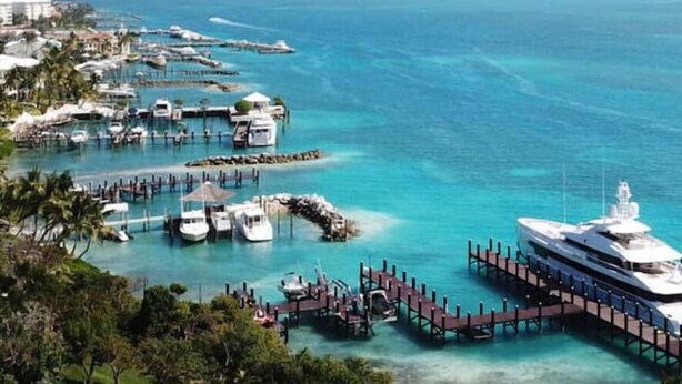Una marina con yates amarrados, un yate blanco grande y un muelle que se extiende al agua.