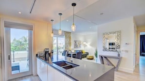 Una cocina moderna con una isla central, iluminación colgante y vistas al exterior.