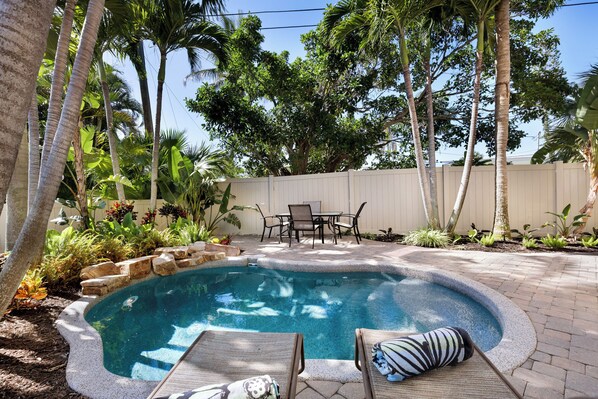Un jardin avec une piscine, des chaises longues et une table de patio.