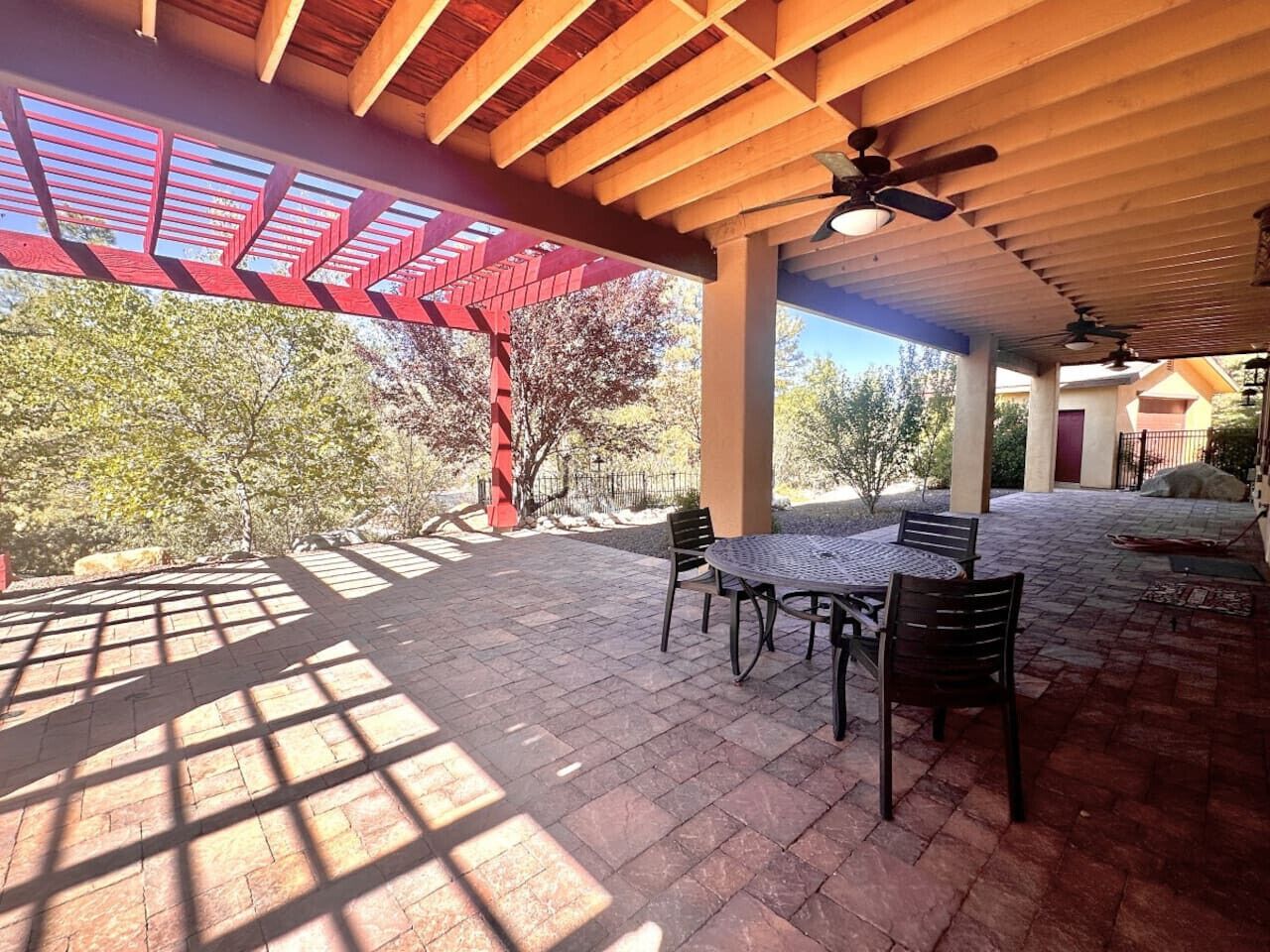 An outdoor patio with a covered seating area, a table, and chairs.