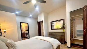 A bedroom with a bed, a ceiling fan, a dresser, a mirror, and a walk-in closet. - Villa Hermosa- Guest Quarters (Prescott)
