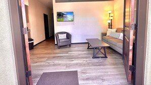 A room with a sofa, a chair, a table, a painting on the wall, and a lamp. - Villa Hermosa- Guest Quarters (Prescott)