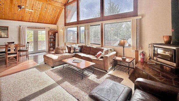 A spacious living room with a large wooden ceiling, a cozy sectional sofa, a fireplace, and a dining area with a table and chairs. - NEW - Peakview Lodge - Fireplace- Views (Prescott)