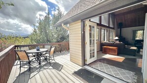 A wooden deck with outdoor furniture, a sliding glass door leading to an interior living space, and a view of trees and mountains in the background. - NEW - Peakview Lodge - Fireplace- Views (Prescott)