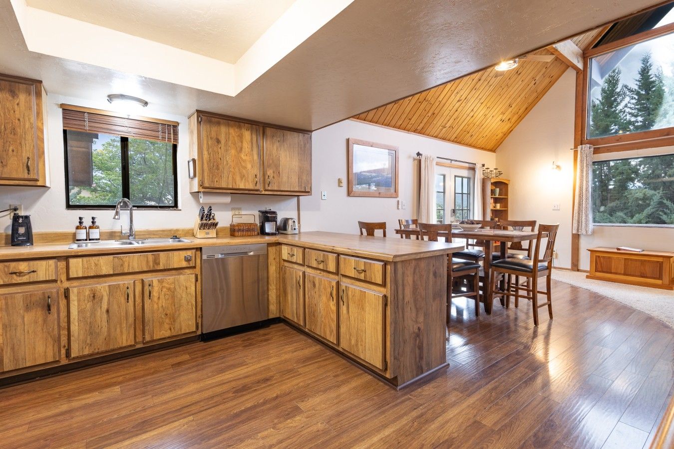 A kitchen with wooden cabinets, a dishwasher, and a dining area with a table and chairs.