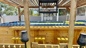 A wooden deck with a bar area, outdoor seating, and a hot tub. - Sunset By The Sea 3052 - FMB, Family Friendly (Fort Myers Beach)