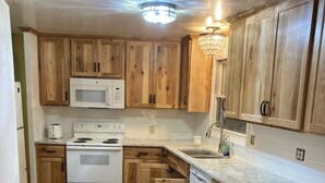 A kitchen with wooden cabinets, a microwave, a stove, and a sink.