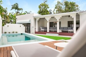 Ein moderner Poolbereich im Freien mit Holzterrasse und Liegebereich.