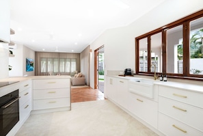 A modern kitchen with white cabinetry and a large window.