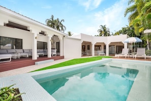 A modern pool area with a clear pool, a wooden deck, and lounge chairs.