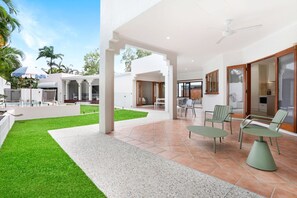 Eine moderne Außenpatio-Terrasse mit Pool, Rasen aus Kunstgrün und Sitzgelegenheiten.
