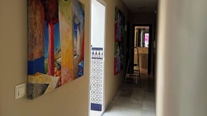A hallway with colorful abstract paintings on the walls, a white door, and a ladder in the background. - Apartment in Centro de Ronda, dream city (Ronda)