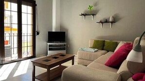 A living room with a sofa, coffee table, TV, and two wall-mounted shelves with decorative items. - Apartment in Centro de Ronda, dream city (Ronda)