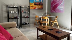 A modern living room with a sofa, a wooden coffee table, and a dining area with chairs and a table. There are two black shelving units with various items on them. - Apartment in Centro de Ronda, dream city (Ronda)