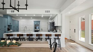 A modern kitchen with a central island, bar stools, and a dining table. - 4\2.5+ LAKE HOUSE — Fish & Swim @DOCK; LakeMat; Kayak; PaddleBoard; King & Queen (Montgomery)