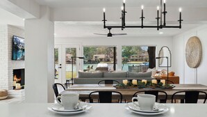 A dining area with a white table, black chairs, and a view of a pool and outdoor seating. - 4\2.5+ LAKE HOUSE — Fish & Swim @DOCK; LakeMat; Kayak; PaddleBoard; King & Queen (Montgomery)