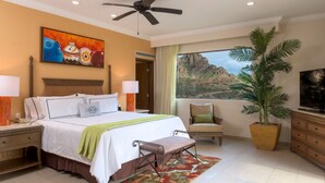 Una habitación de hotel con una cama, un escritorio, una silla, un televisor, un ventanal con vistas a la montaña y un ventilador de techo.