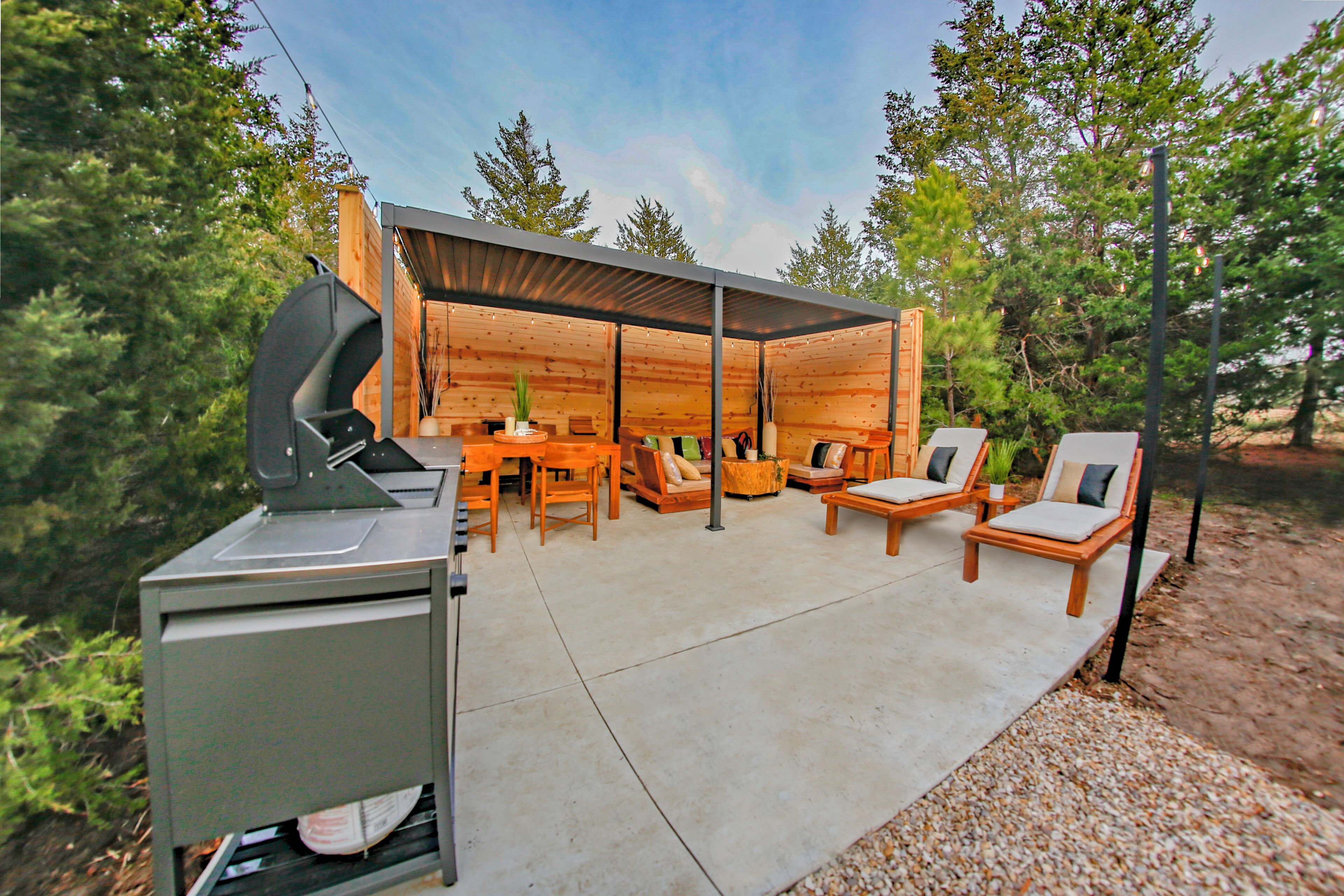 An outdoor patio area with a grill, seating, and a covered section with a table and chairs.