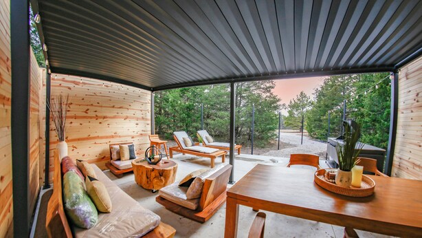 A wooden interior with a dining table, lounge chairs, and a sofa area.