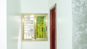 A narrow hallway with a window, a door, and recessed lighting on the ceiling. - Le Tamarin (Dakar)