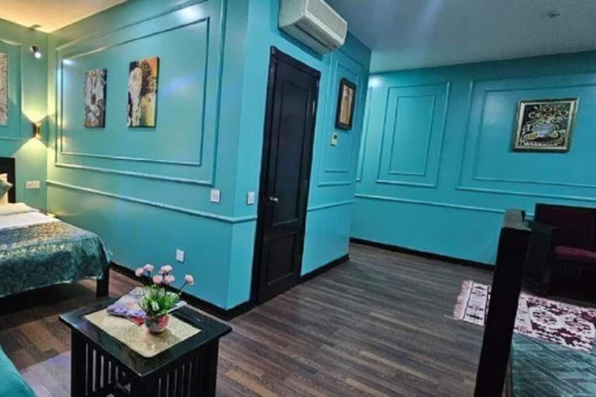 A hotel room with a bed, a small table with a vase of flowers, and a chair.