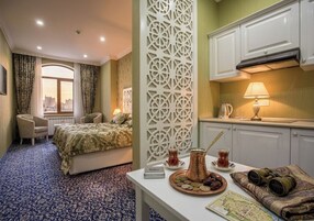 Hotelkamer met een bed, een eettafel met een dienblad eten en drinken, een decoratieve scheidingswand en uitzicht op de stad door een raam.