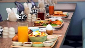 Un bufé de desayuno con diversos platos, salsas y bebidas sobre una mesa de madera.