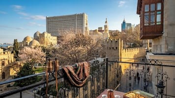 Un balcón con una mesa dispuesta para el té, vistas de edificios históricos y cielo despejado.