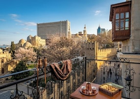 Een balkon met een gedekte tafel voor thee, uitzicht op historische gebouwen en een heldere lucht.