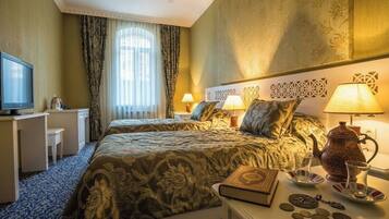 A hotel room with a large bed, two bedside tables, a television, and a decorative headboard.