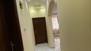 A hallway with a marble floor, a wooden door, and a ceiling with recessed lighting. - Very nice and relaxing (Salalah)