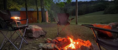 A campsite with a fire pit surrounded by rocks and two folding chairs.