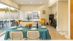 A dining area with a table set for four, a sofa, and a TV in the background. - Peaceful villa w/ pool, BBQ & ping-pong table (Alcantarilha)